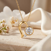 Gold heart moissanite pendant necklace with round cut stones on a lifestyle background.