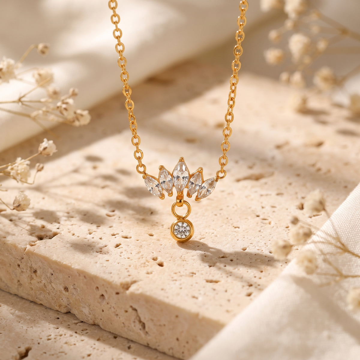 Gold-tone necklace featuring a fan of marquise cubic zirconia and a dangling round stone on textured stone.