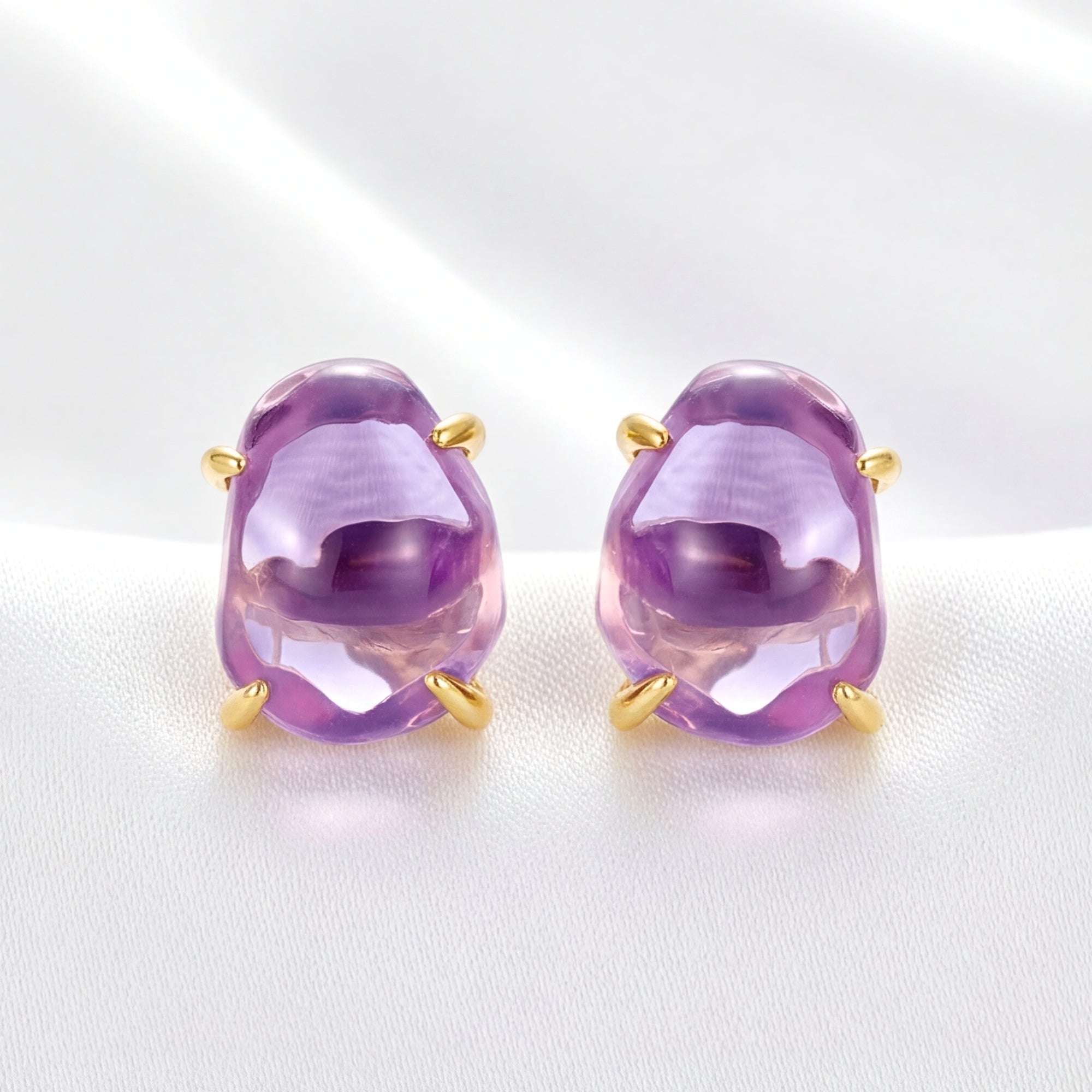 Thalassa oval cut purple simulated amethyst stud earrings in 18K gold vermeil on a white silk background.