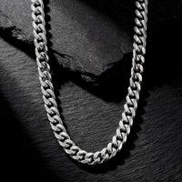 Silver 8mm stainless steel Cuban link chain laid on a dark textured slate background.