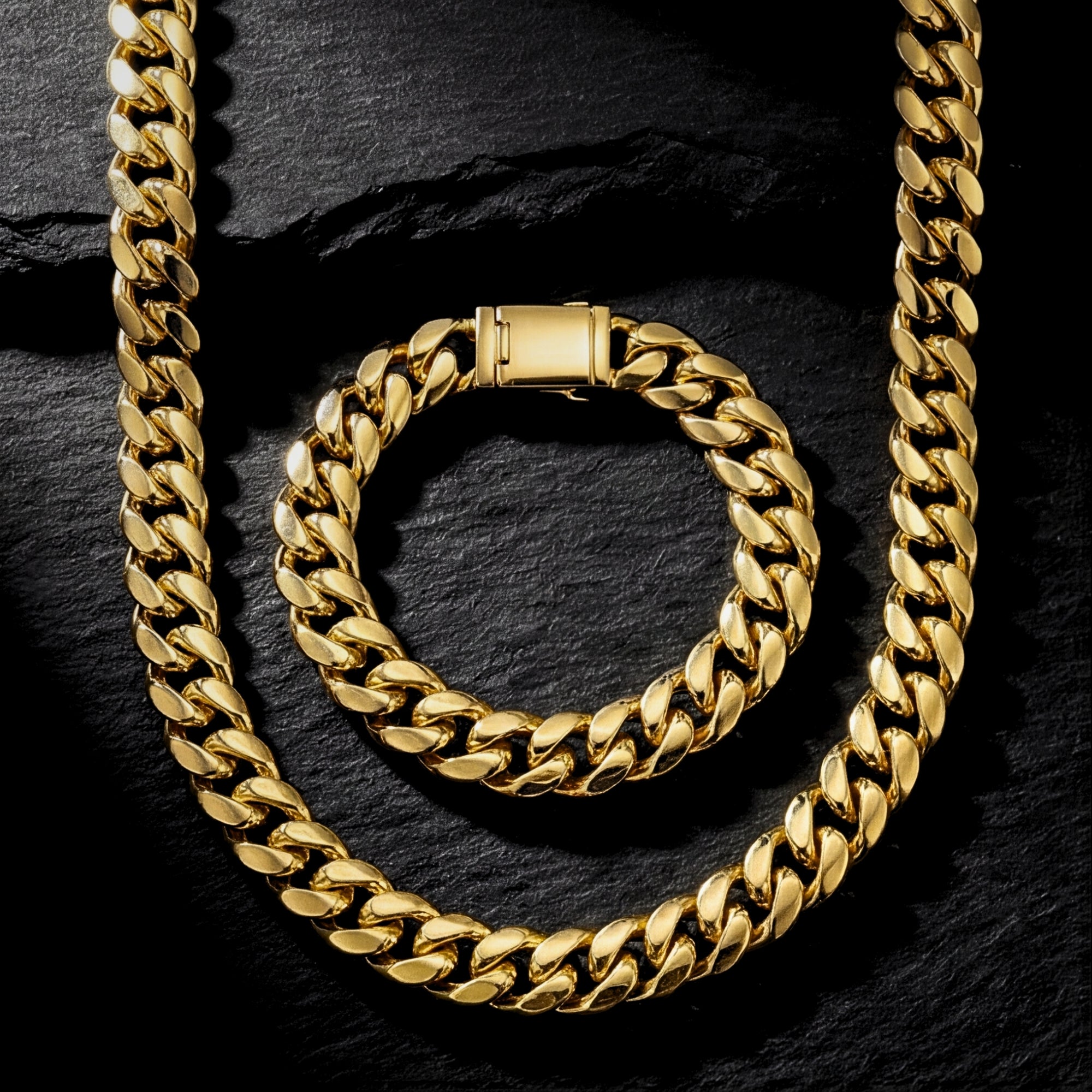 Top view of a 10mm gold stainless steel Cuban link chain and bracelet set on a dark textured stone background.