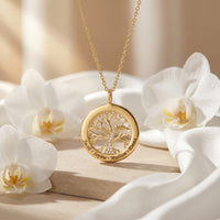 Yellow Gold Tree of Life pendant necklace with simulated diamonds and engraved names, styled with white orchids.