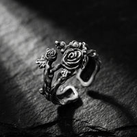 Close-up of the oxidized silver rose vine open ring on a dark slate surface, with carved roses and leaves.