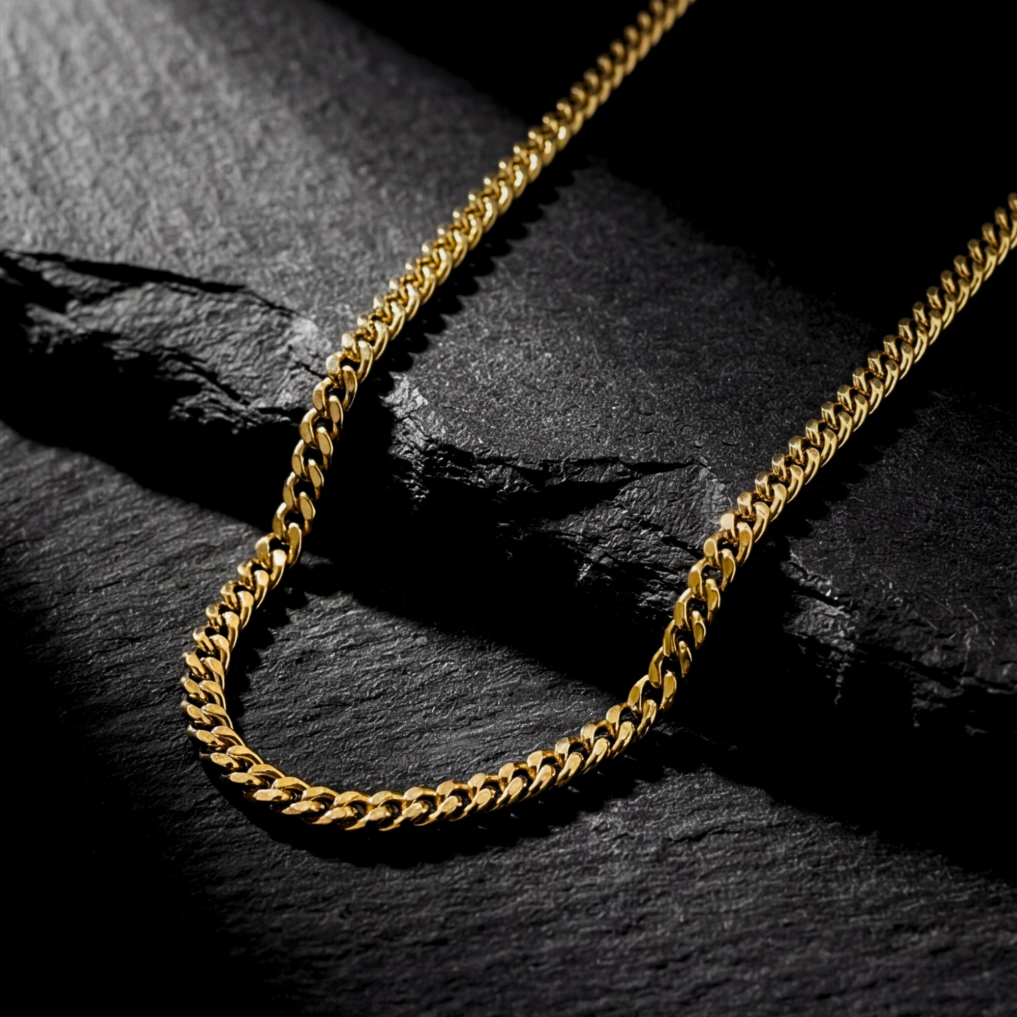 2mm gold Connell curb chain for men displayed on a dark textured stone background.