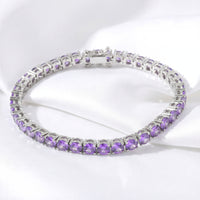Round purple simulated amethyst tennis bracelet in stainless steel displayed on white draped fabric.