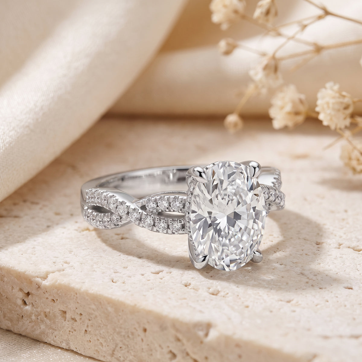 The Infinity Twist Ring resting upright, featuring a large oval stone on a pavé-set twisted band.