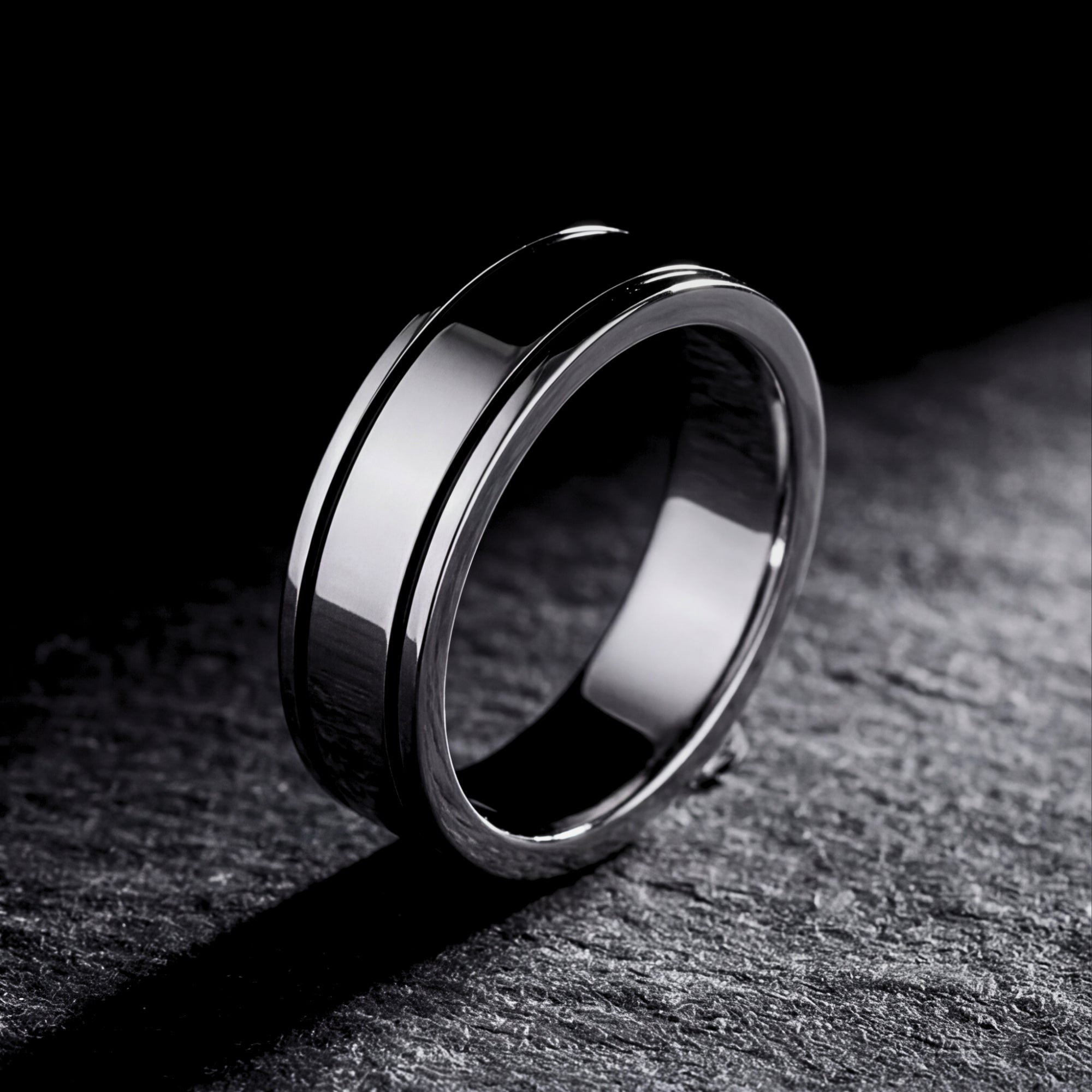 Silver stainless steel Horizon band ring with a grooved design on a dark textured stone surface.