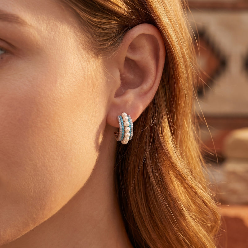 Close-up of a model wearing a silver turquoise and pearl C-hoop earring.