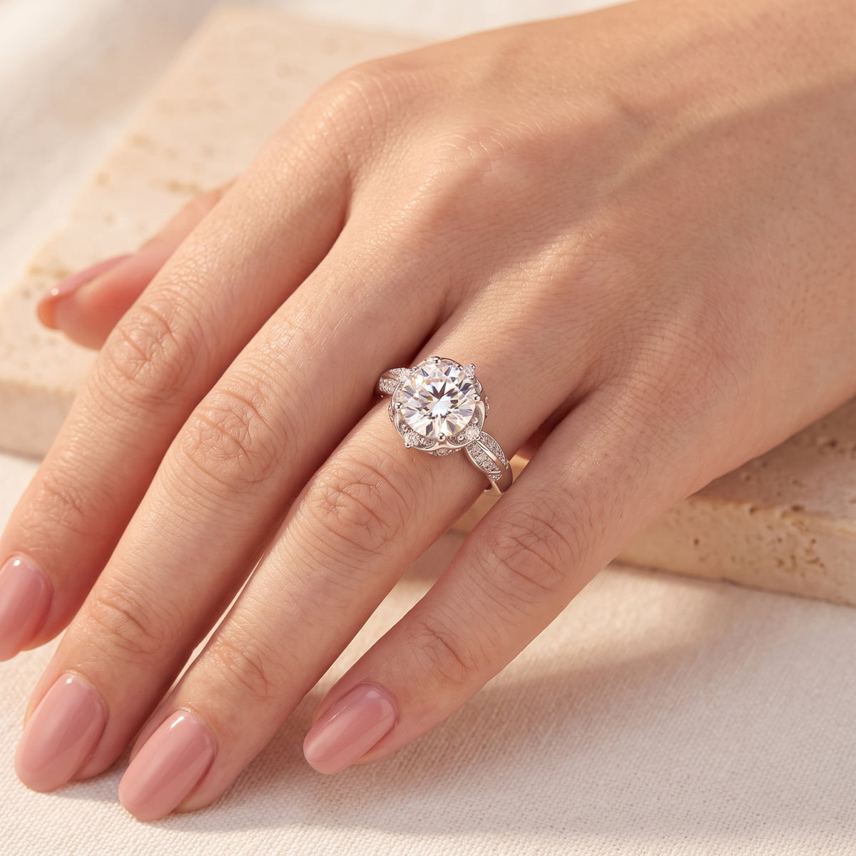 Top-down view of the silver lotus solitaire ring worn on a ring finger with manicured nails.