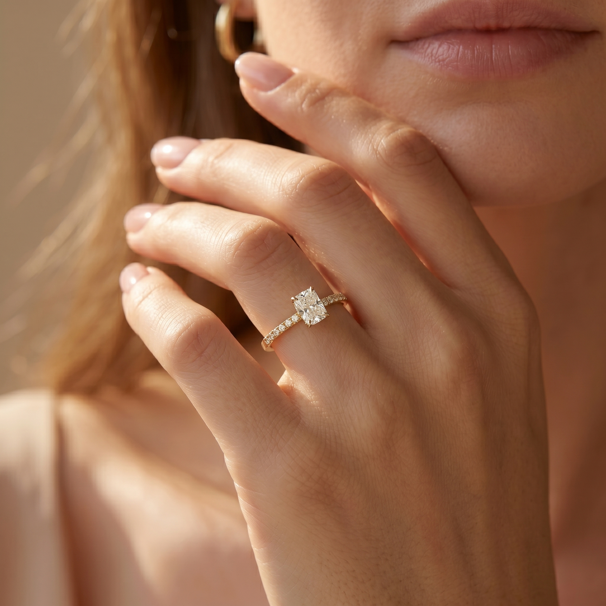 A woman wearing a cushion-cut moissanite engagement ring on her finger, set in yellow gold.