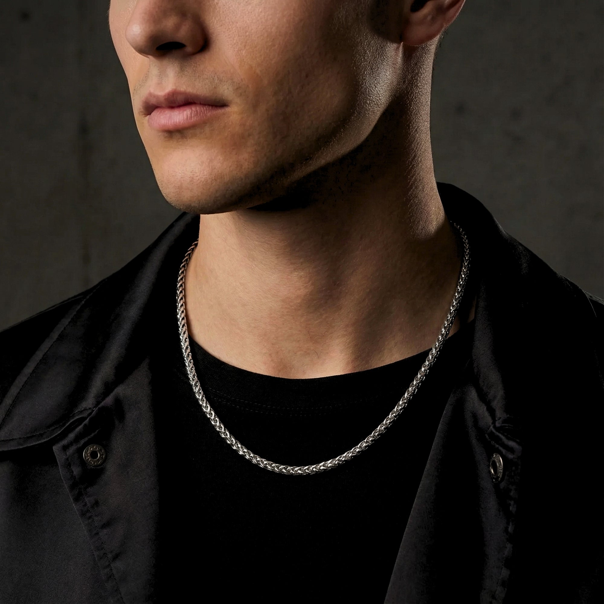 Men's silver stainless steel wheat chain necklace worn by a model over a black t-shirt.