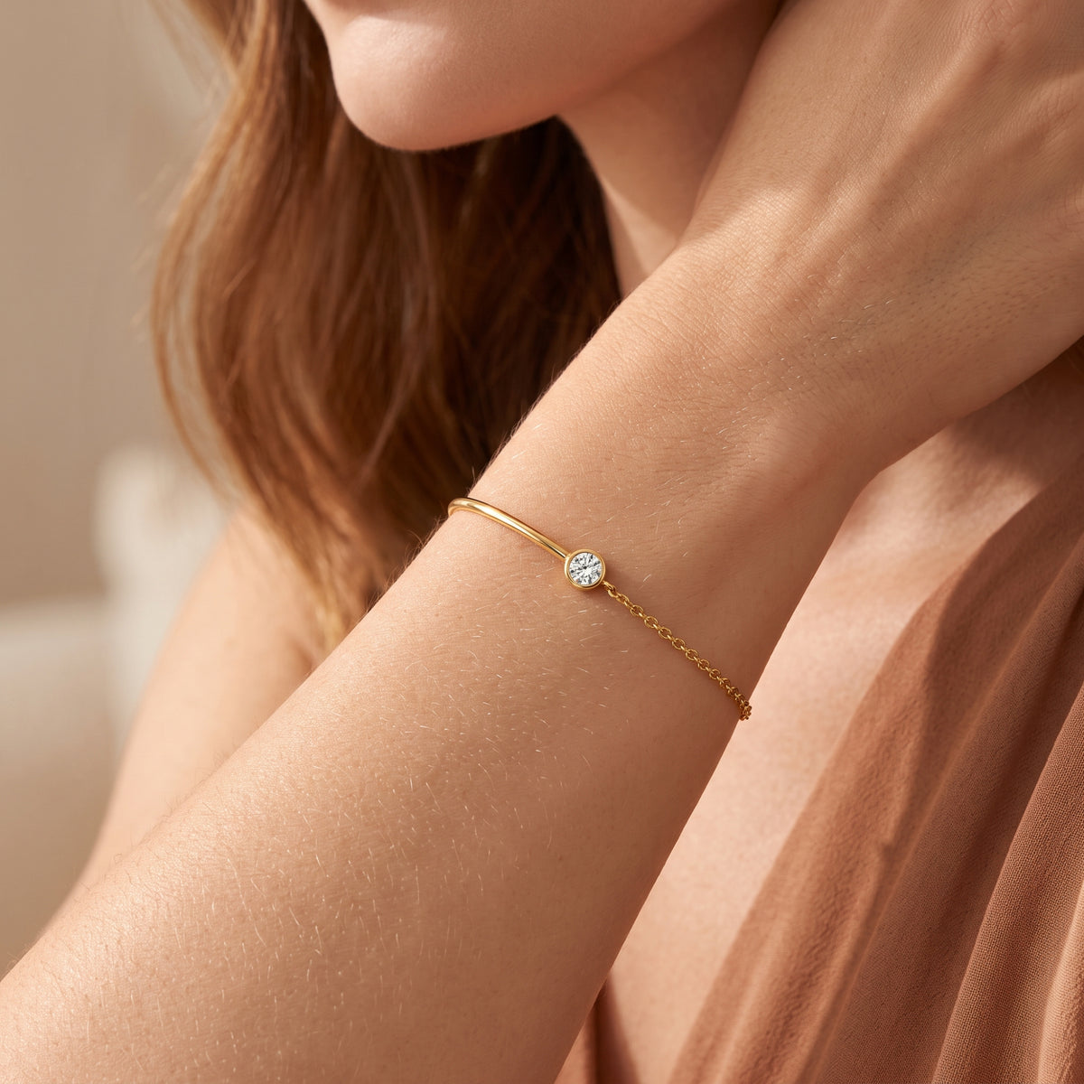 Close-up of a model wearing the gold-tone bezel station cuff bracelet with a round clear stone on her wrist.