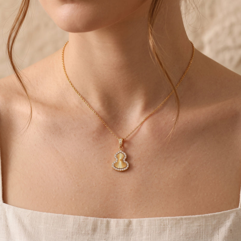 Gold PVD stainless steel Sorsha necklace with gourd pendant worn by a model.