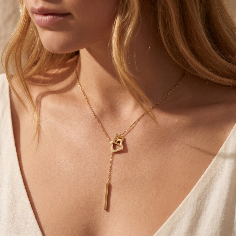 Model wearing the gold-color square link lariat necklace with a white V-neck neckline.