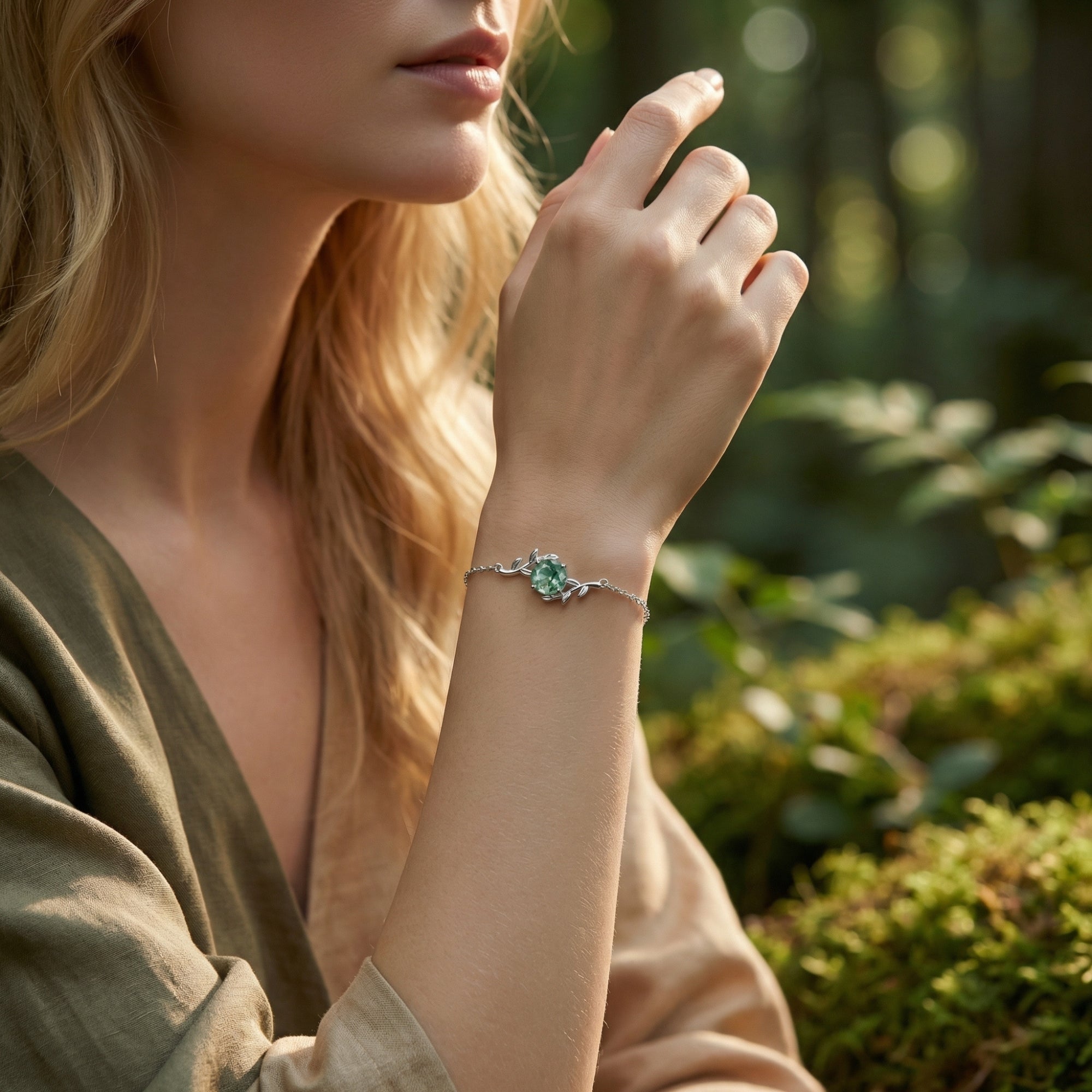 Model wearing the vine wrap sterling silver moss agate bracelet on her wrist in a natural forest setting.