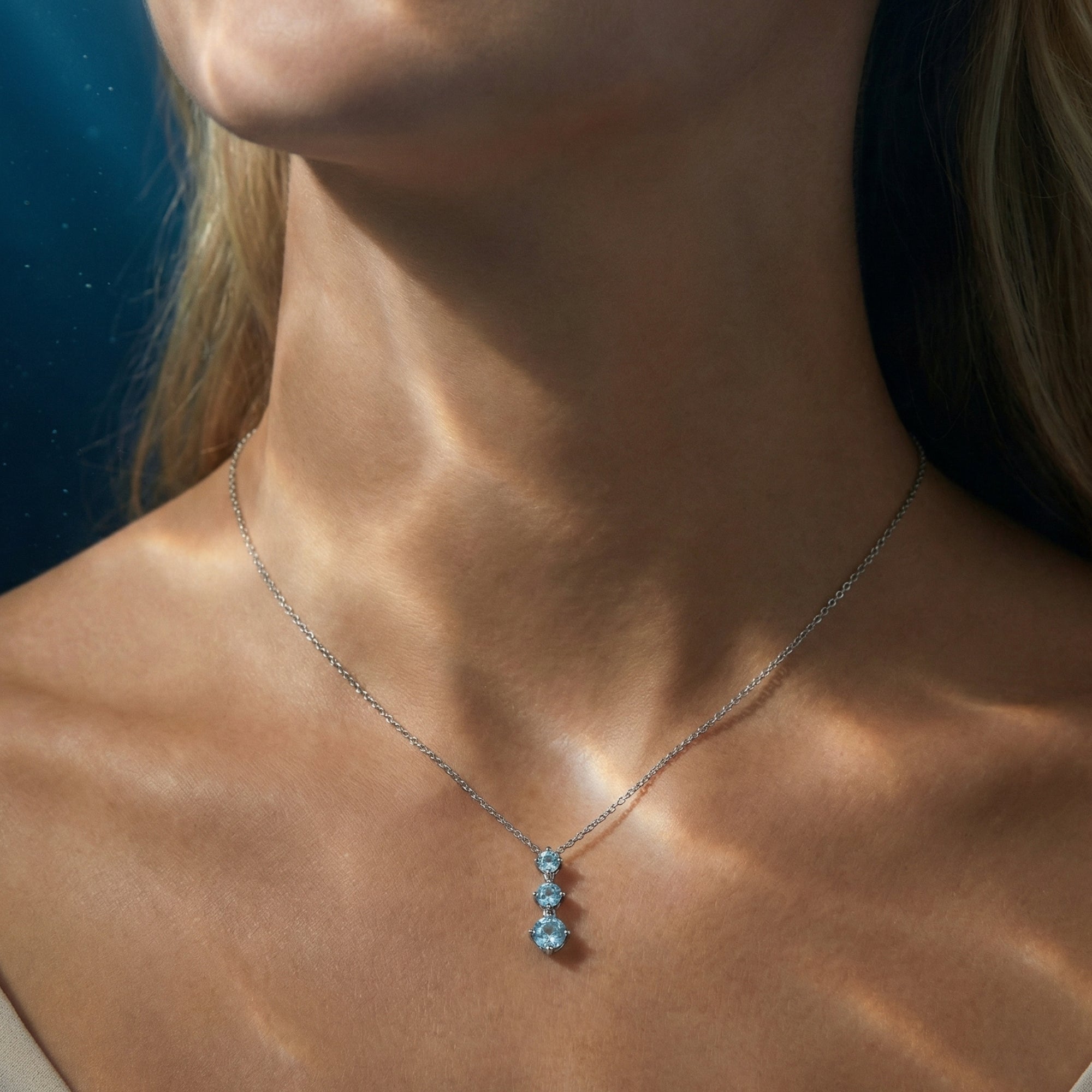 Close-up of a model wearing the graduated round aquamarine necklace in platinum on a delicate chain.