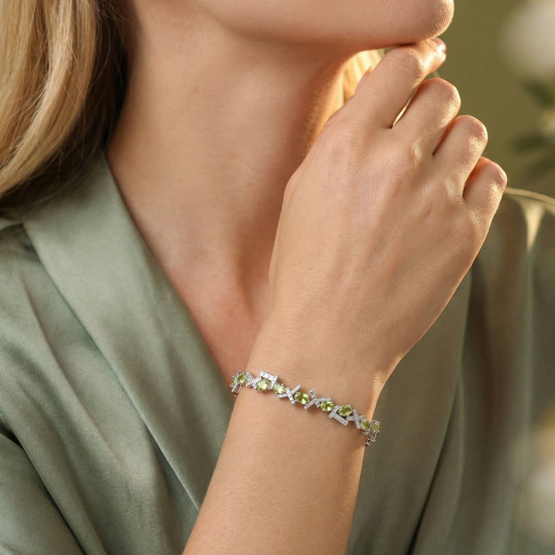 Model wearing the Olyria oval cut green peridot bracelet in sterling silver on her wrist.