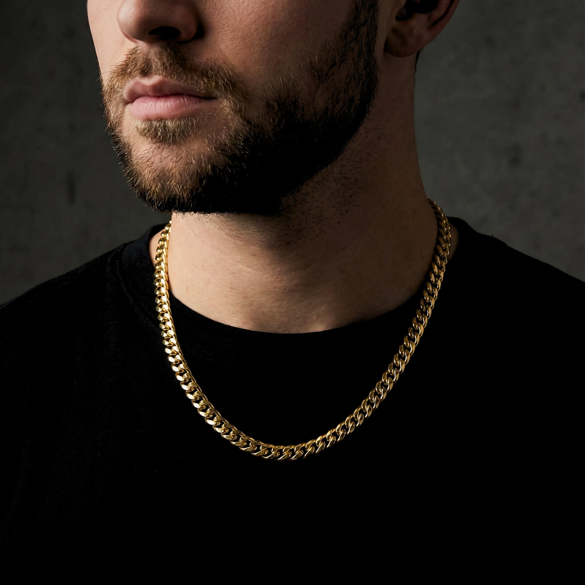 Man wearing a 6mm gold stainless steel Cuban chain over a black t-shirt.