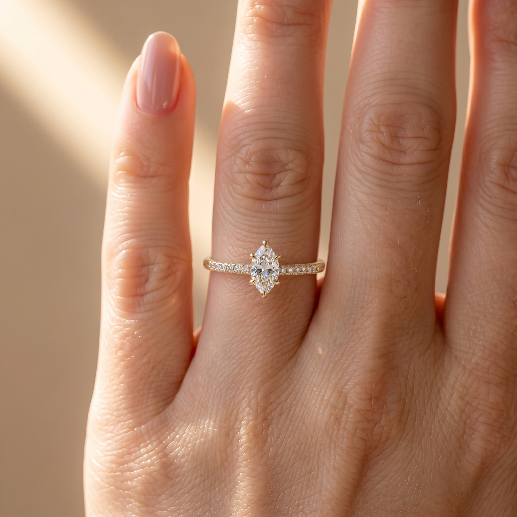 A close-up view of the yellow gold marquise-cut moissanite ring with a sparkling pavé band worn on a finger.