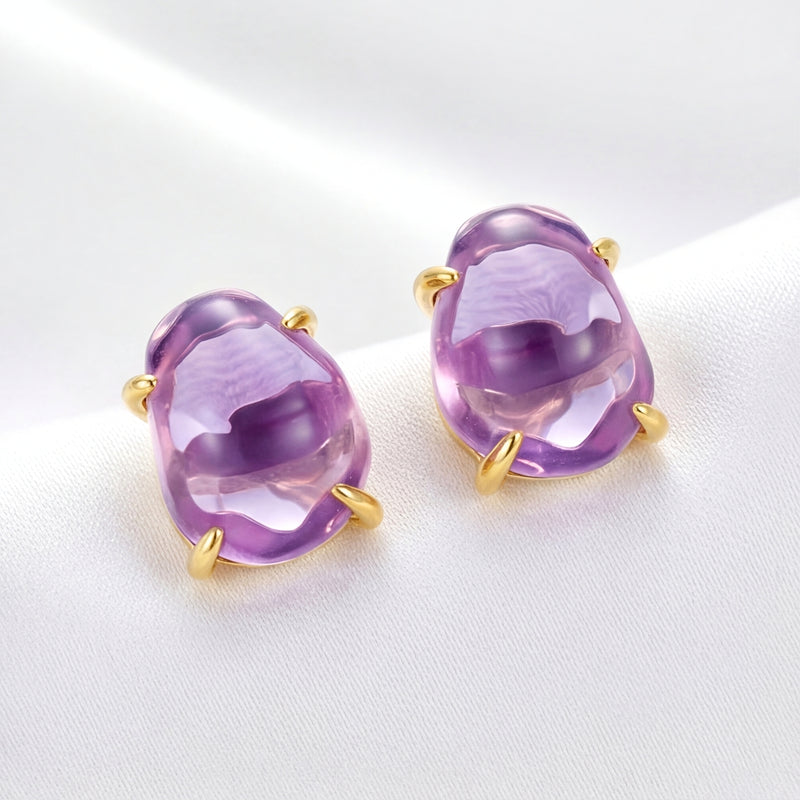 Angled view of Thalassa 18K gold vermeil stud earrings featuring oval cut purple simulated amethyst stones.