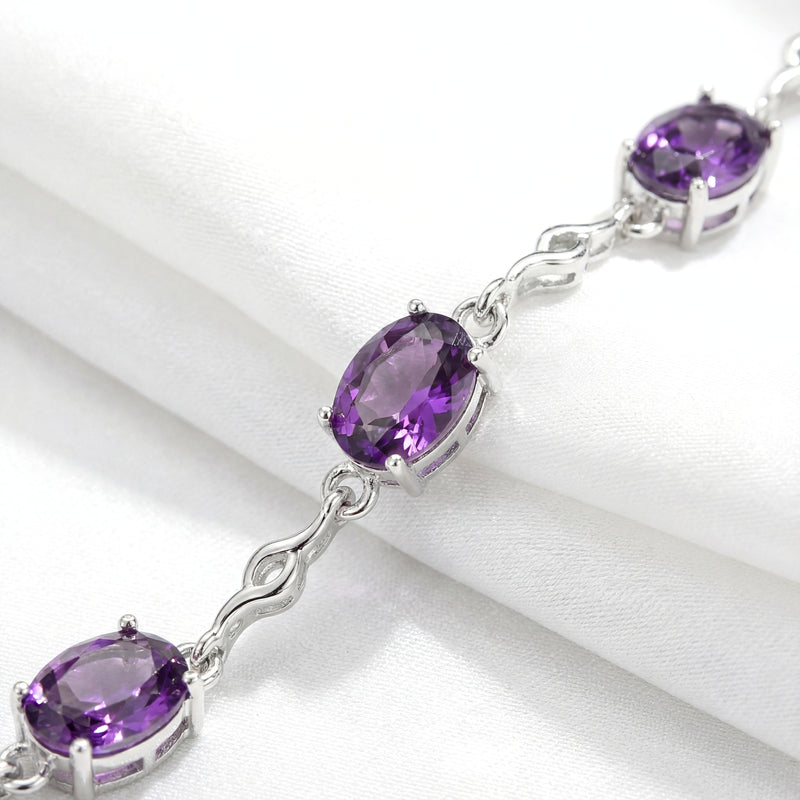 Macro shot of oval-cut simulated amethyst stones in sterling silver prong settings on the Estella station bracelet.
