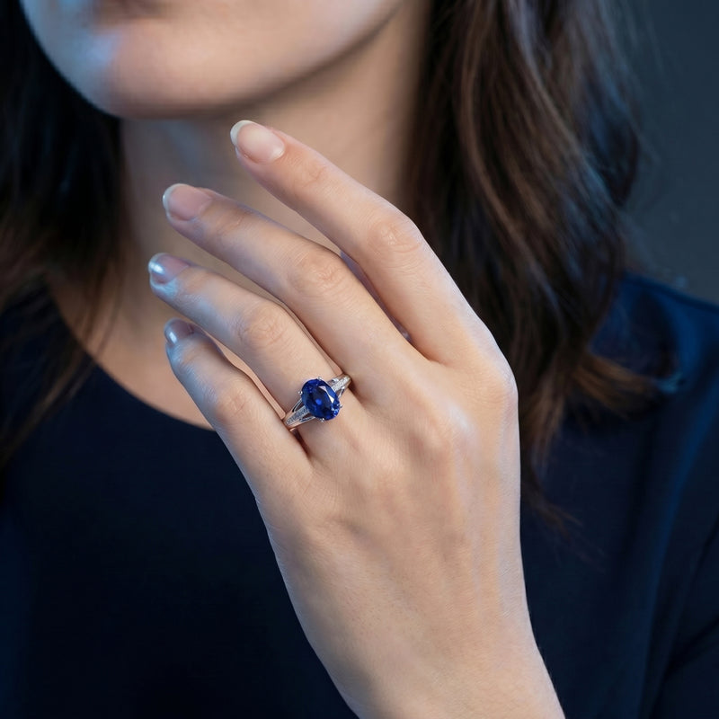 The 18K white gold oval tanzanite and diamond ring worn on a model's hand.