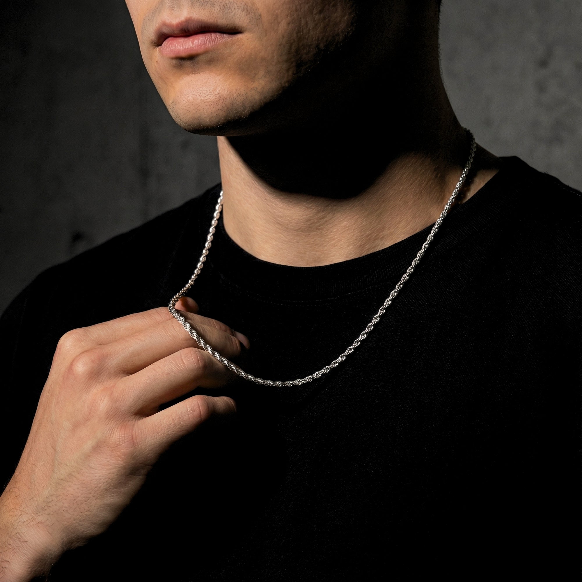 Model holding a silver stainless steel rope chain to demonstrate its thickness and scale.