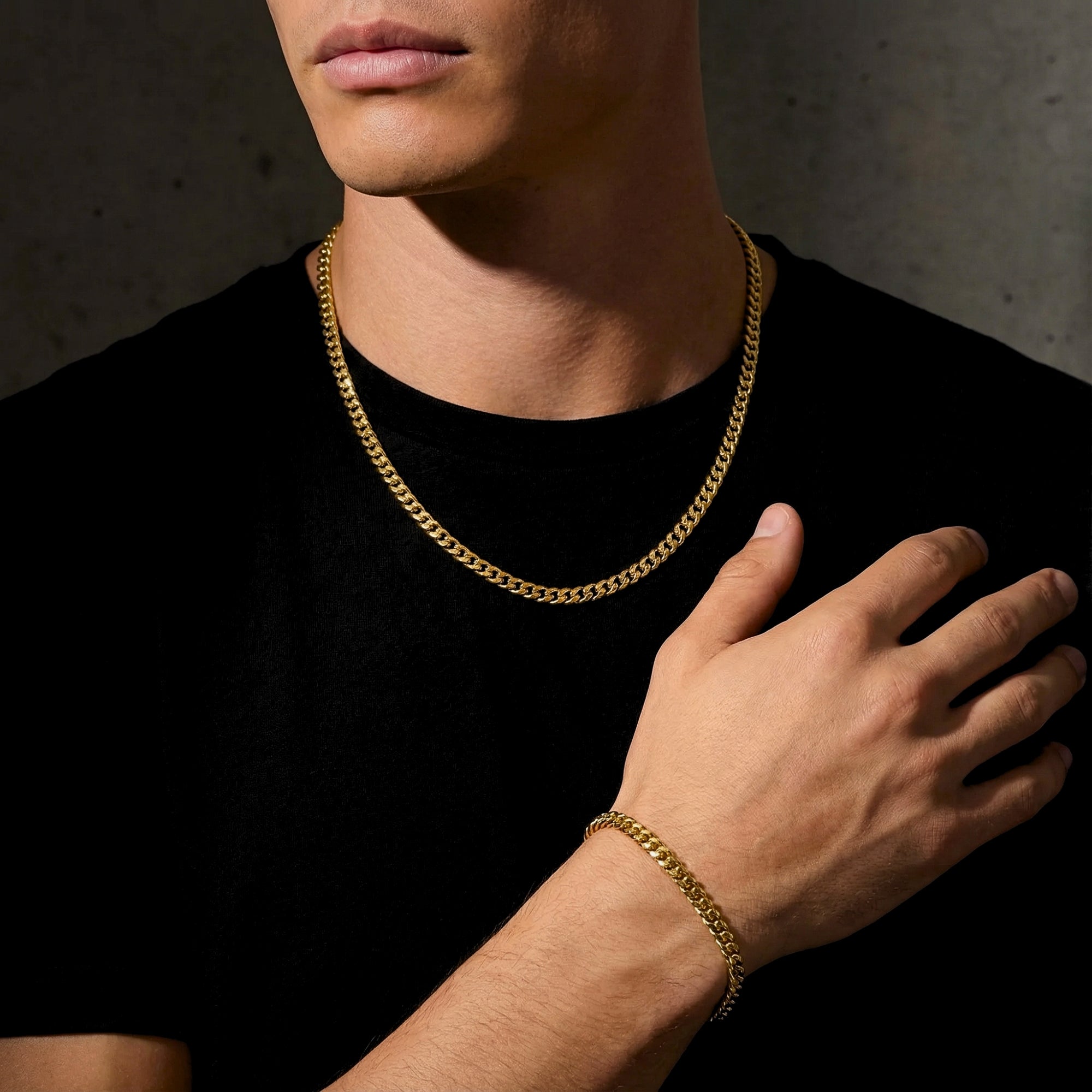 Man wearing a 6mm gold stainless steel Cuban link chain and matching bracelet with a black t-shirt.
