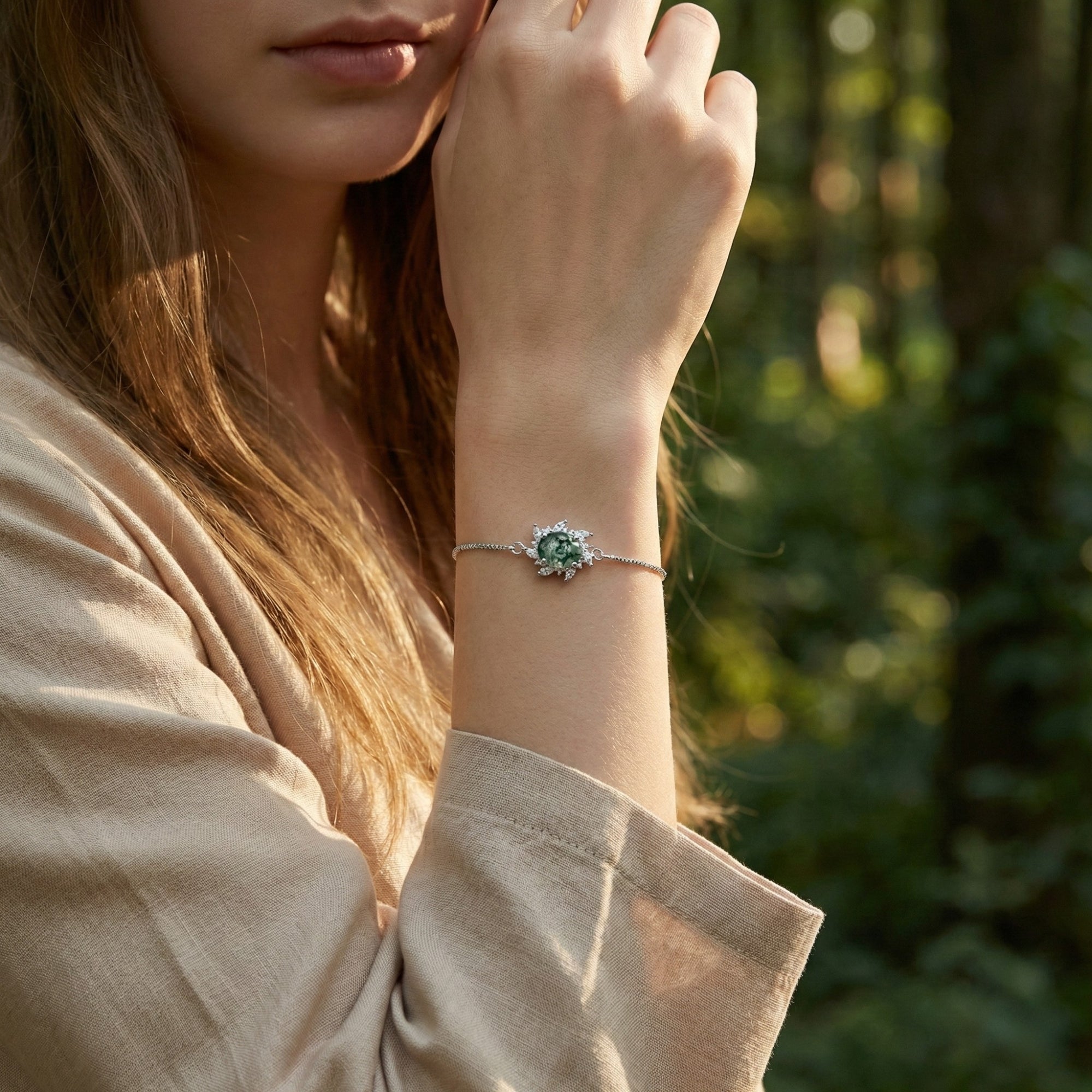 Woman wearing the sunburst moss agate sterling silver bracelet on her wrist in a natural forest setting.