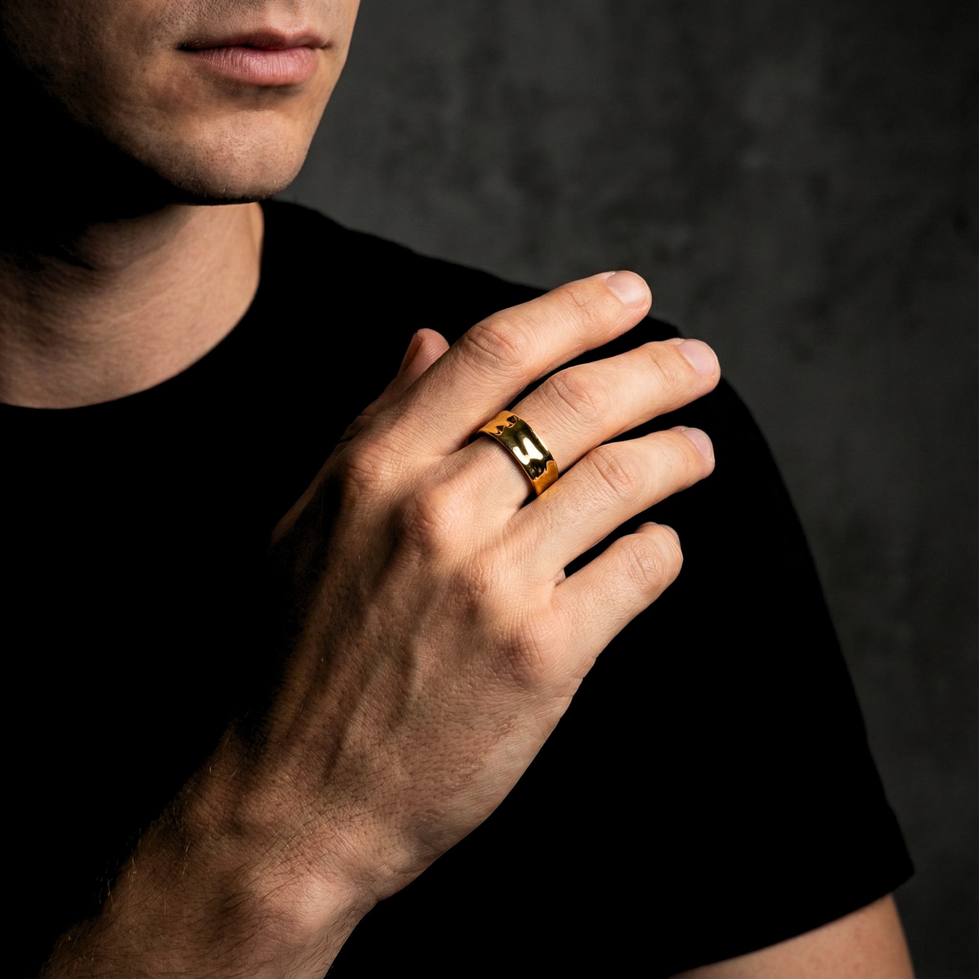 Man wearing the gold stainless steel Origin Flow ring on his ring finger, paired with a black t-shirt.