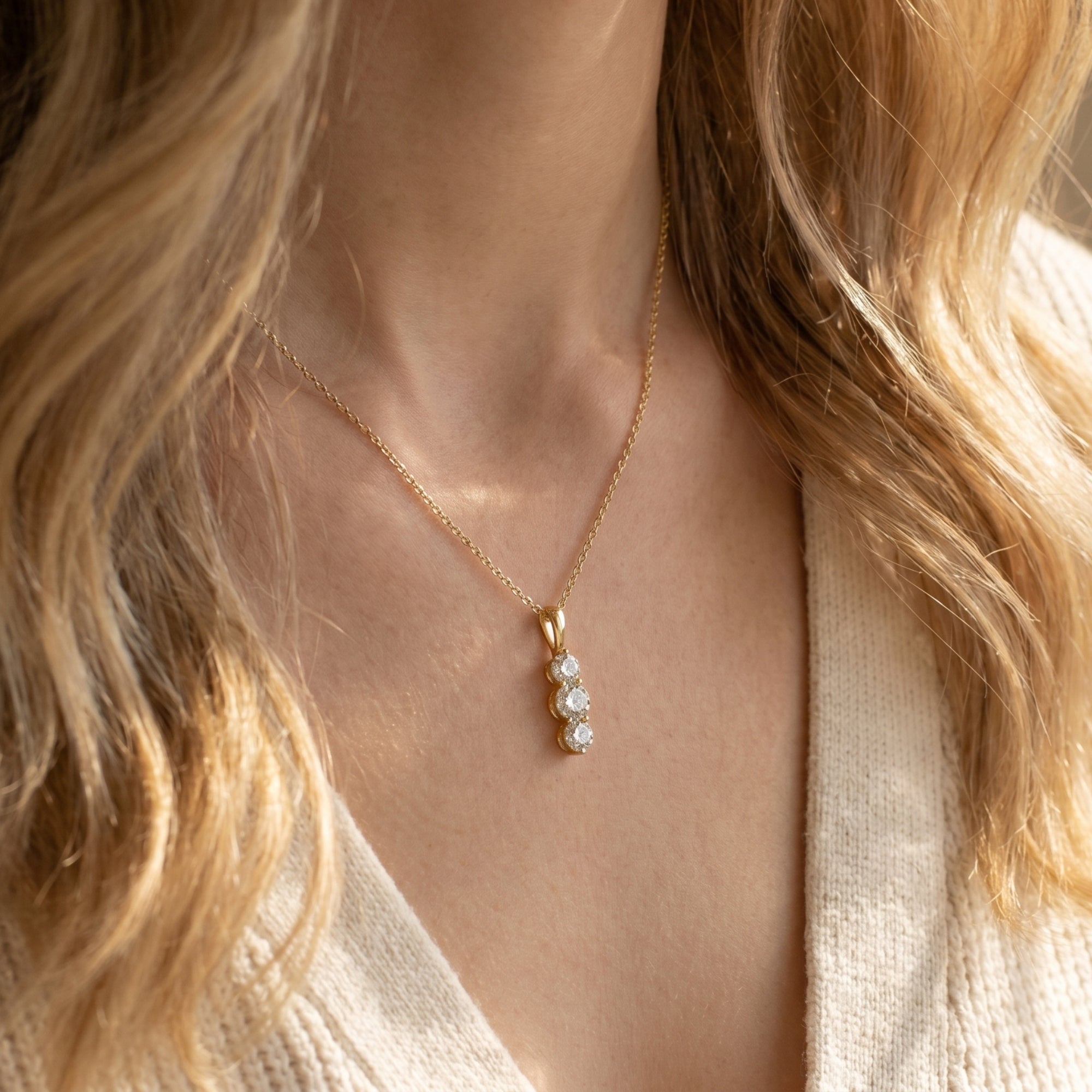 Woman wearing the gold Larisa moissanite pendant with three vertical round stones.