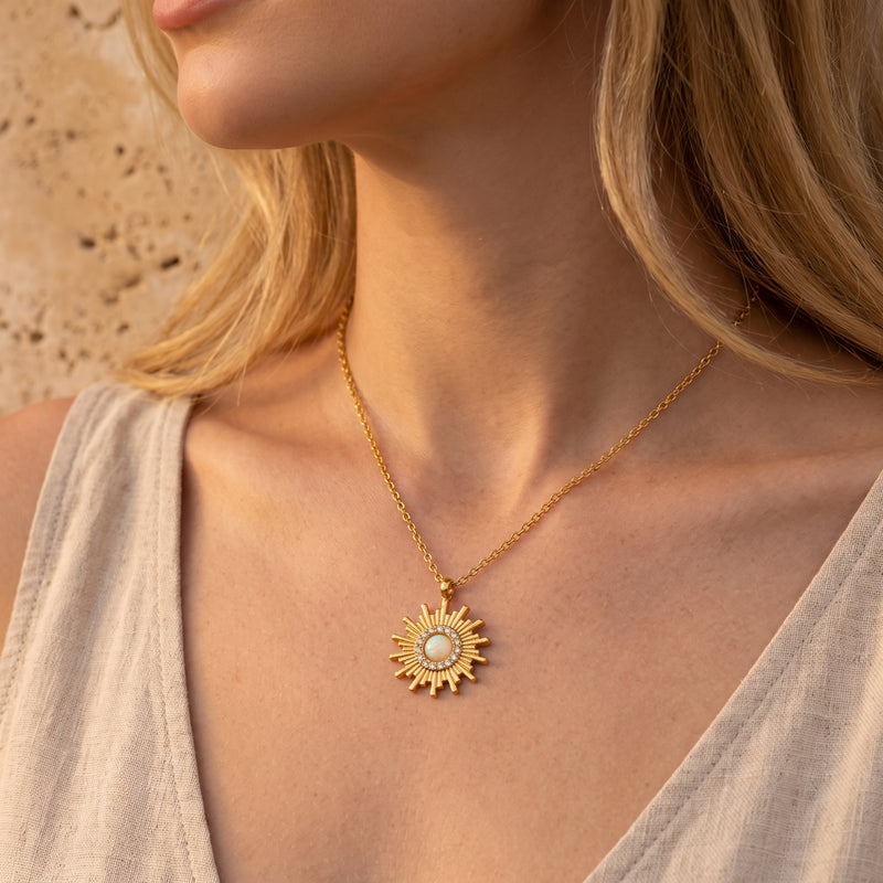 Close-up of a model wearing the gold-tone sunburst opal pendant necklace against a light beige top.