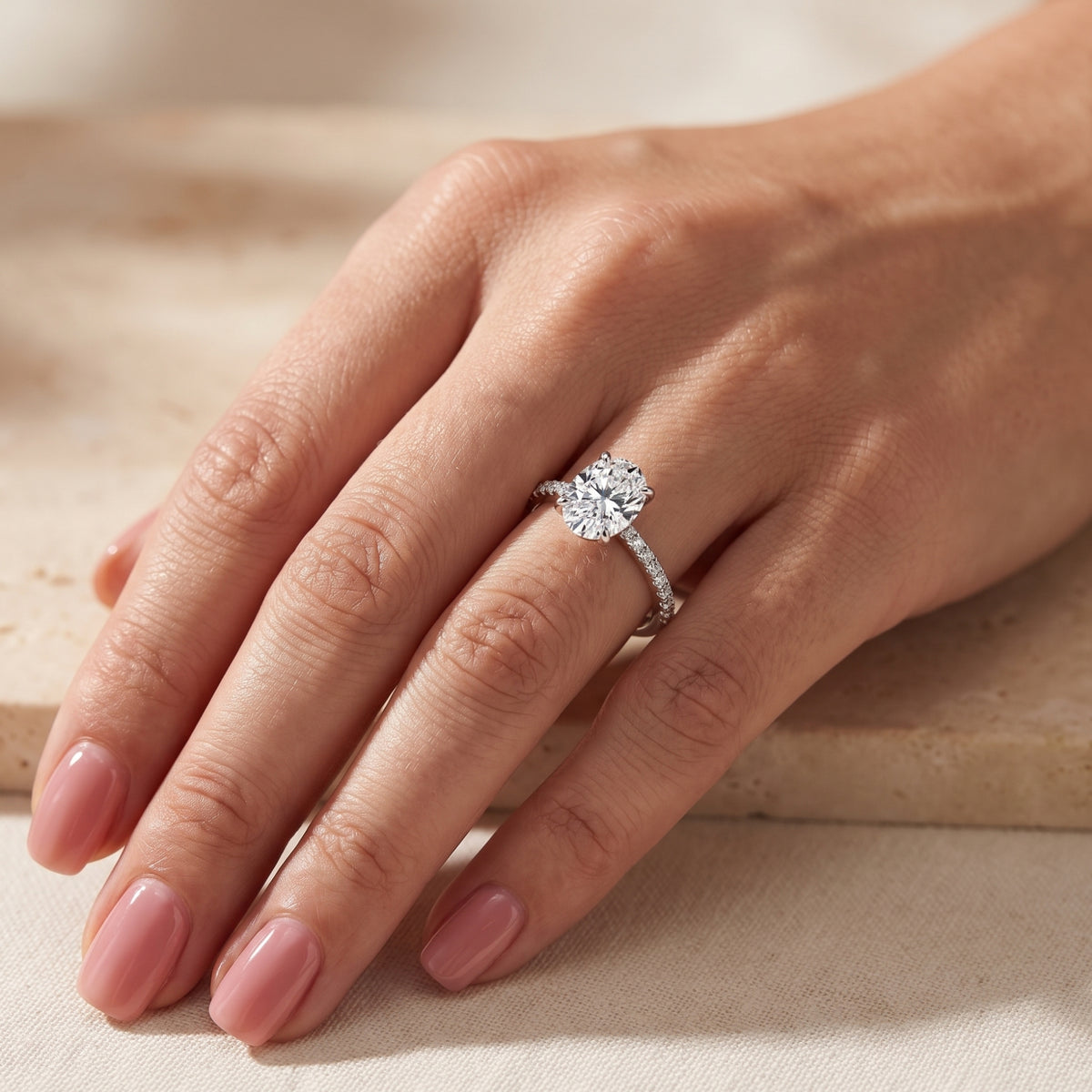 Silver ring with a clear center stone and pavé band worn on a ring finger, shown from an angled hand perspective.