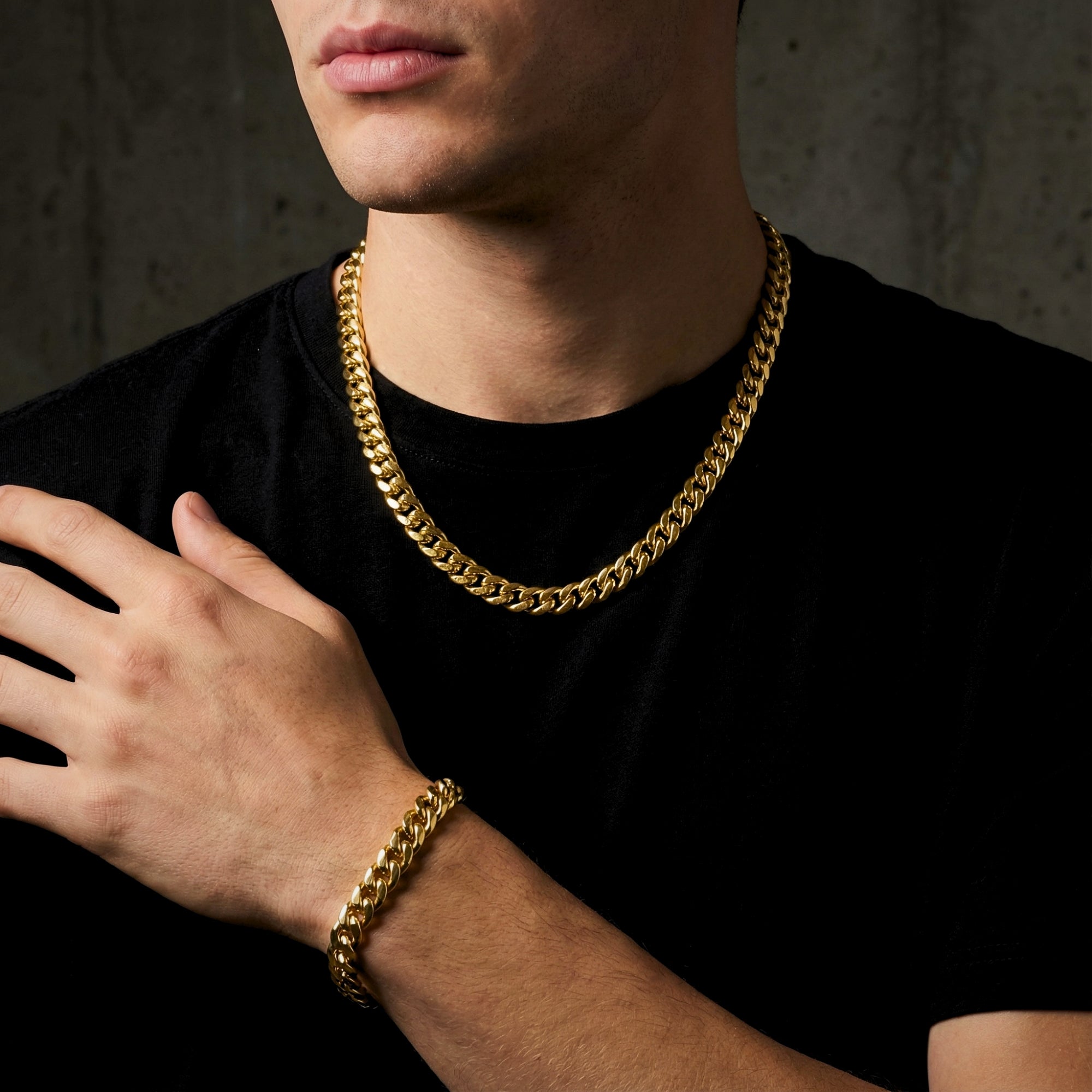 Man wearing a 10mm gold stainless steel Cuban link chain and matching bracelet over a black t-shirt.