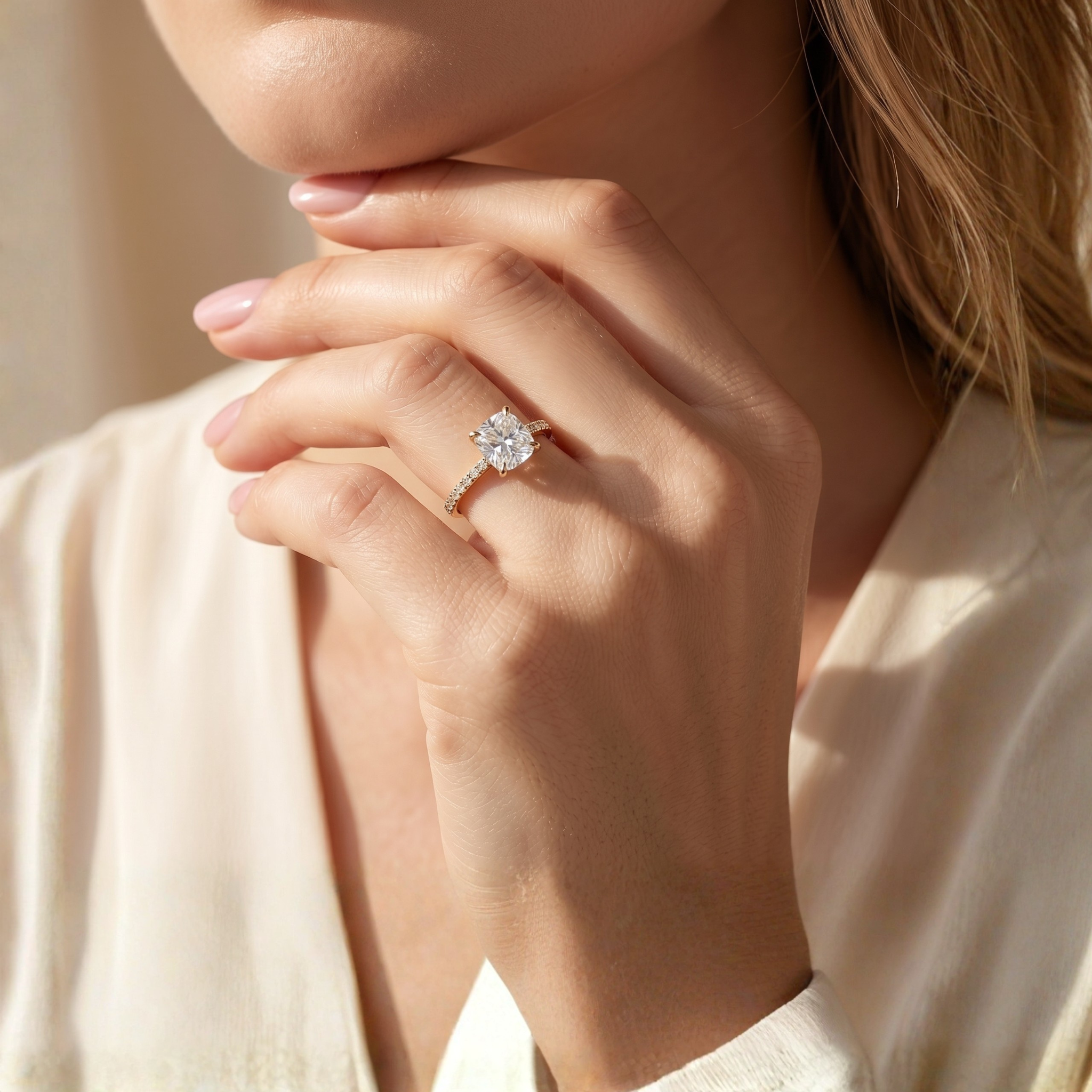 A woman wearing a classic yellow gold cushion-cut moissanite engagement ring with a pavé diamond band.