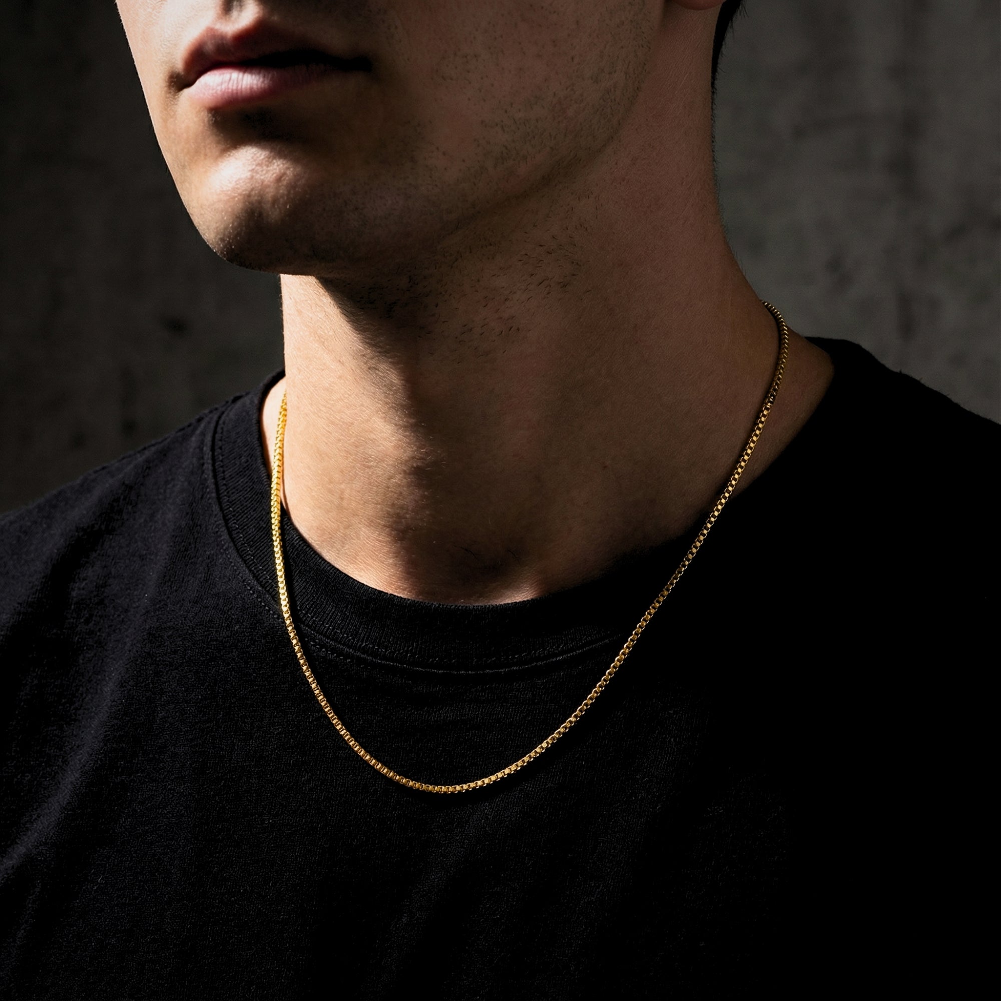 Side view of a man wearing the gold Boxed In box chain necklace, showing how it sits on the neck.