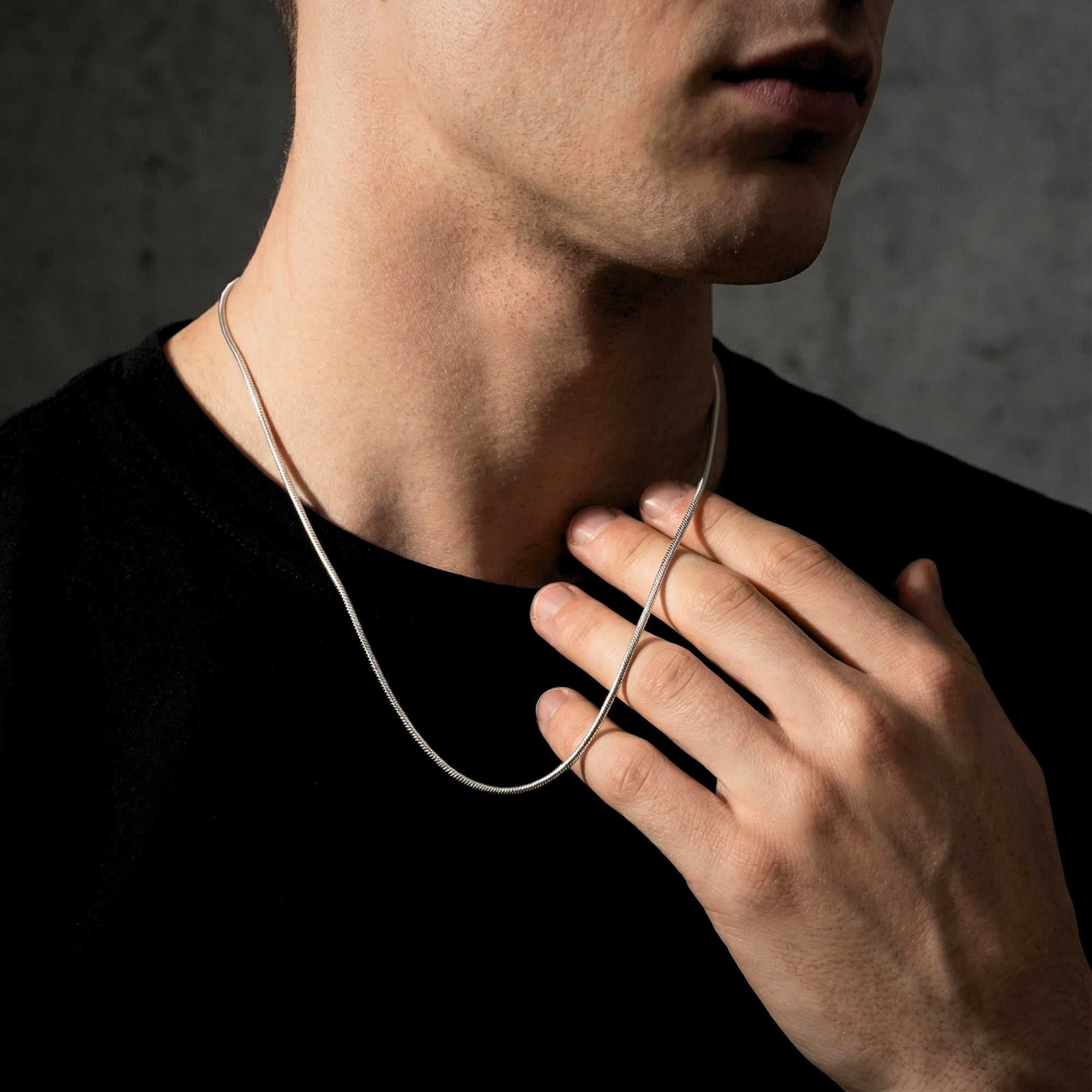 Men's silver stainless steel square link chain necklace worn by a model over a black t-shirt.