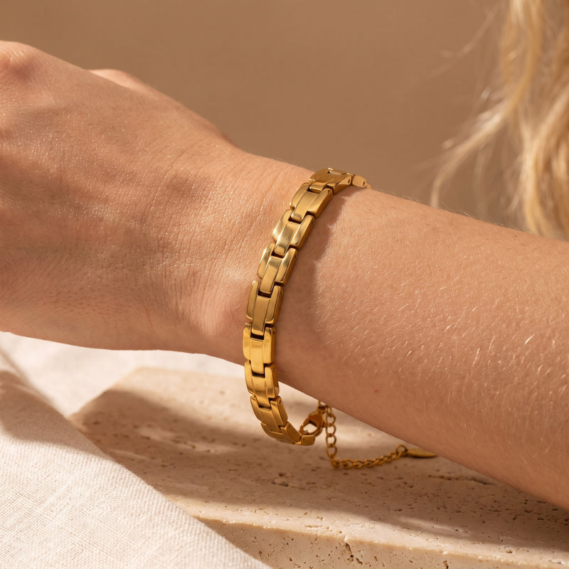 Gold-tone sculpted link bracelet worn on a wrist, showcasing its thick interlocked link structure.
