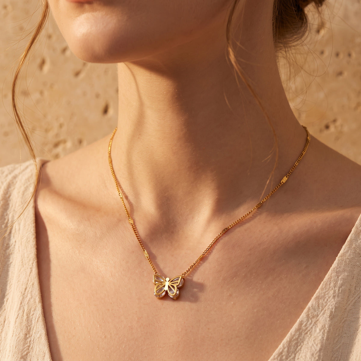 On-model close-up view of the gold-tone openwork butterfly necklace worn at the neck.