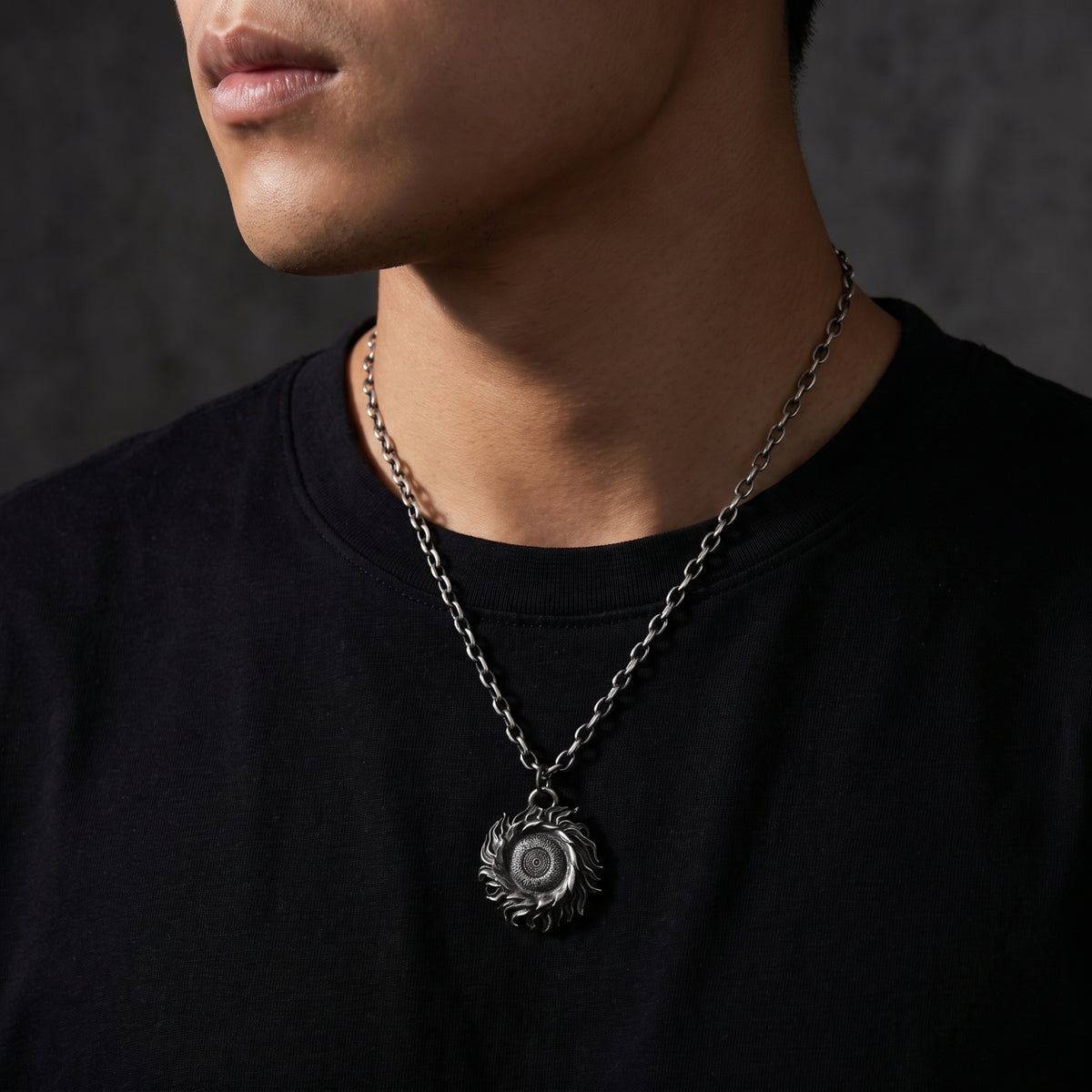 Cropped view of a man wearing the silver solar flare pendant necklace over a black T-shirt.
