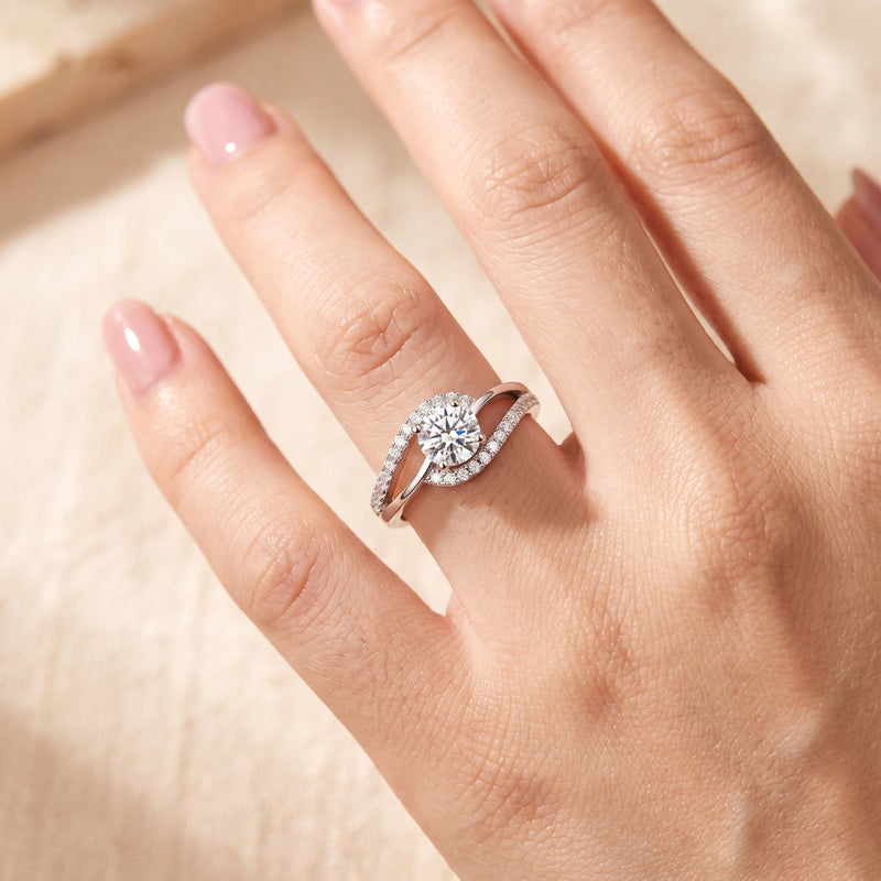 Close-up of a hand wearing the silver bypass ring with a round clear center stone and pavé accents.