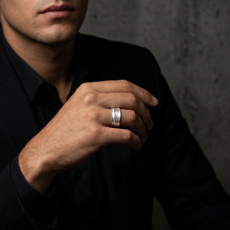 Man in a black jacket wearing the textured silver open-band ring on his ring finger