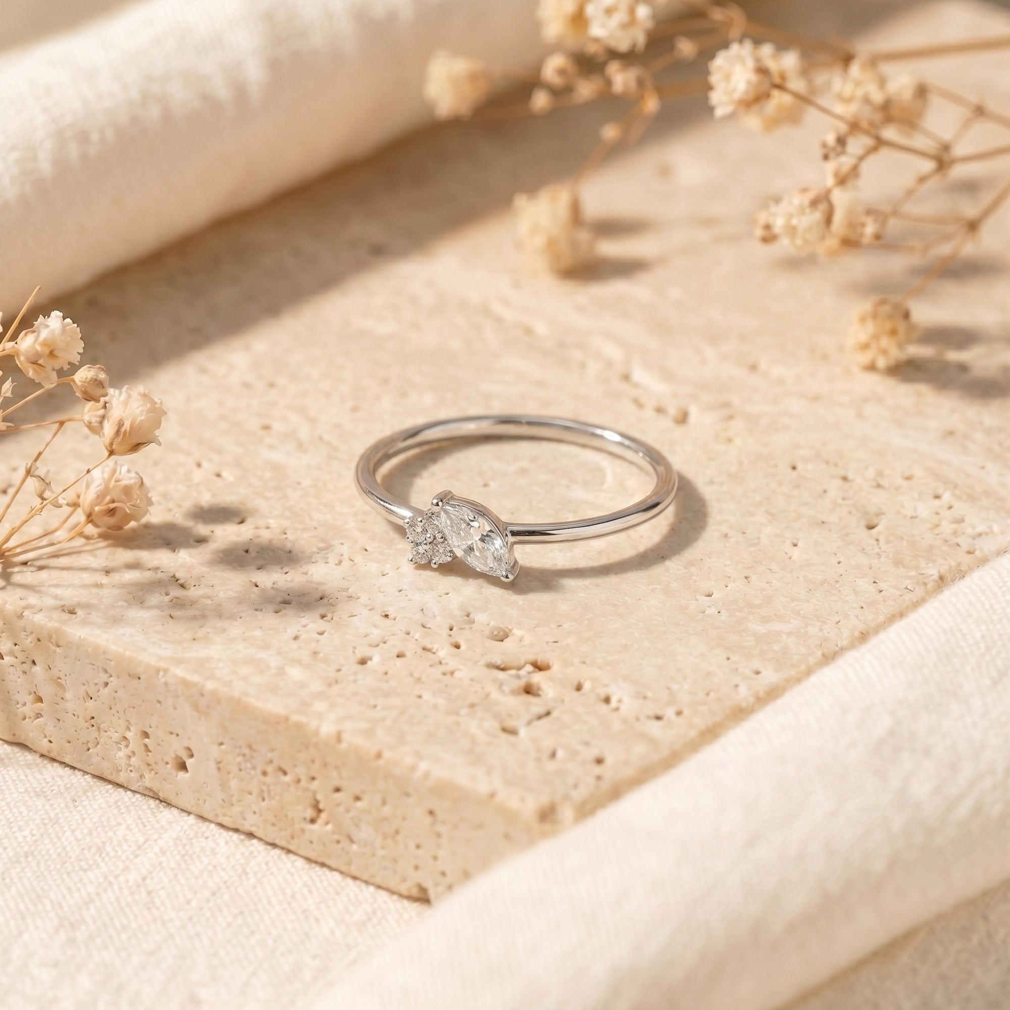 Close-up of marquise moissanite solitaire ring in silver on stone.