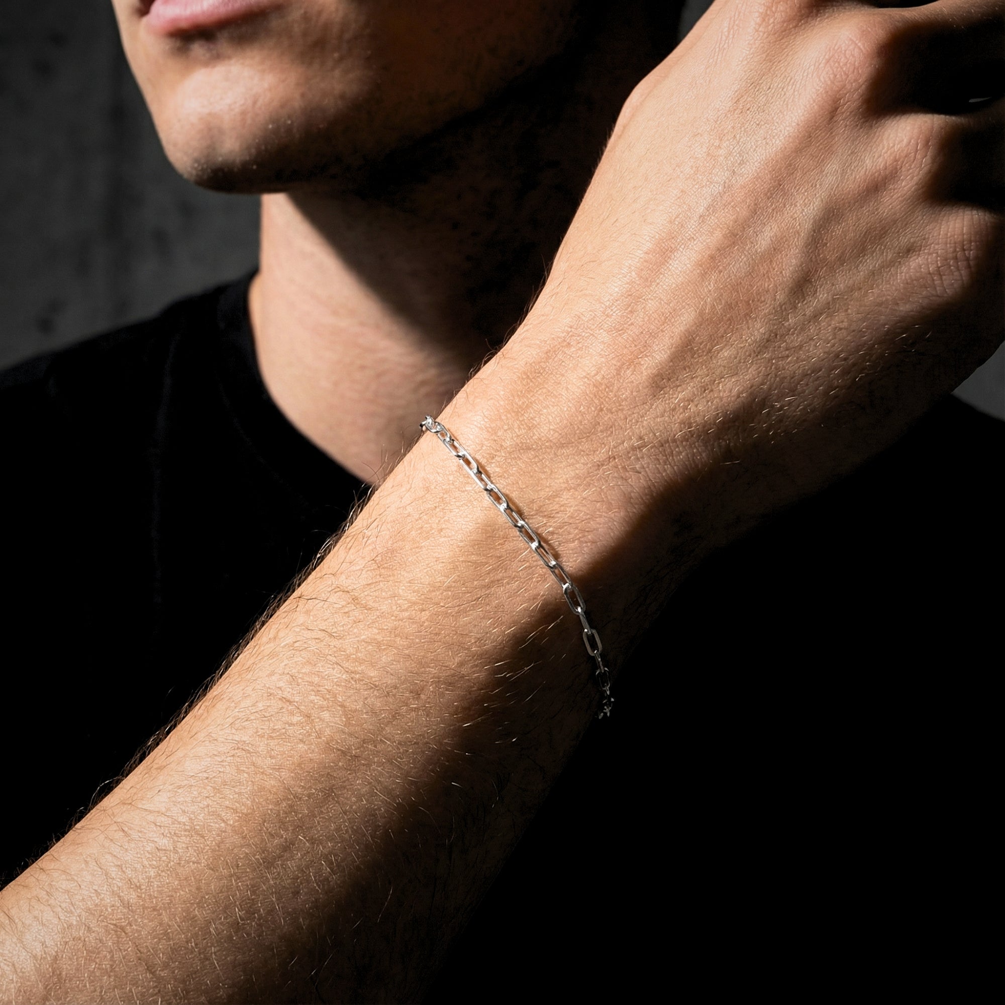 Men's silver stainless steel clip chain bracelet worn on the wrist, showcasing its minimalist design.