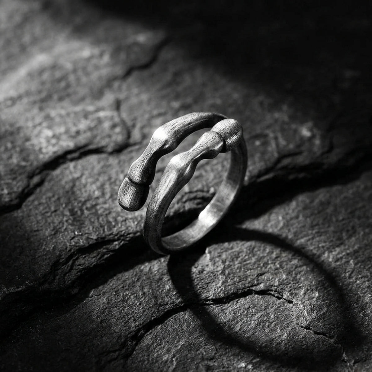 Angled view of a textured 999 fine silver open-band ring standing on a dark, rough rock surface.