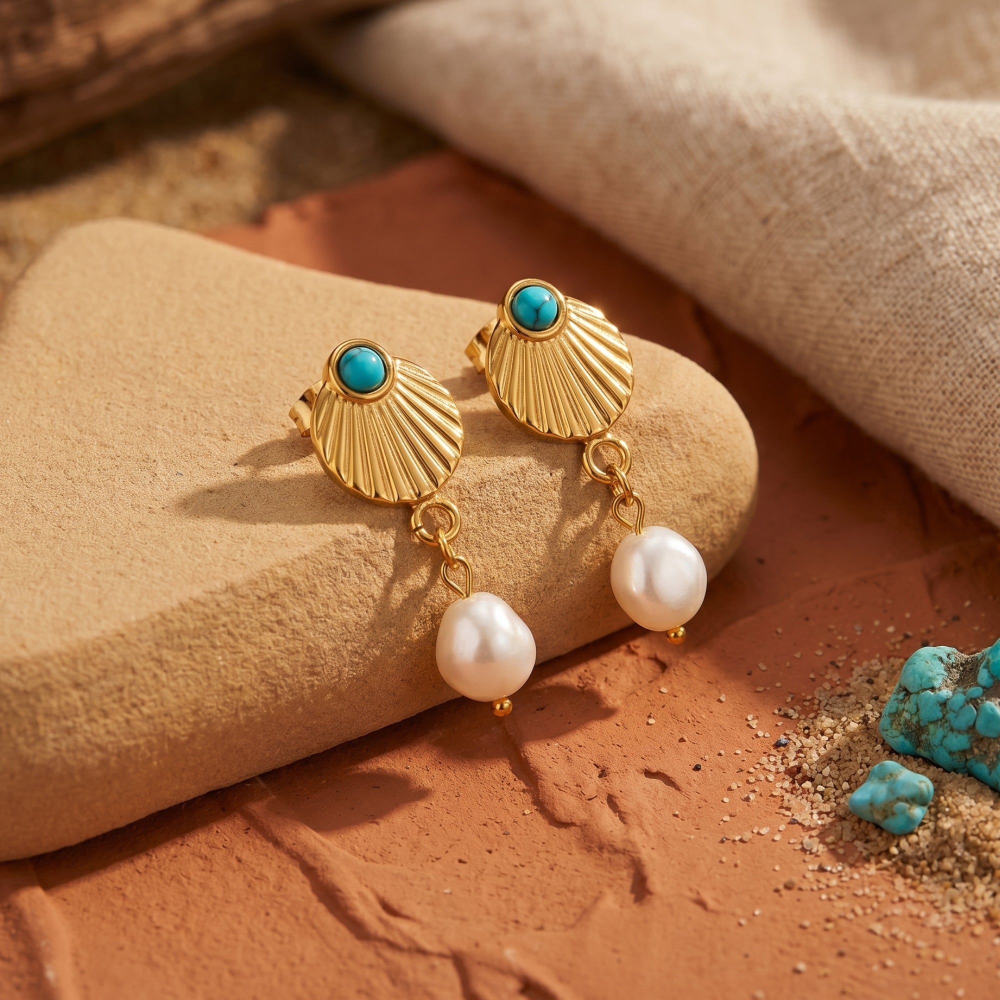 Detail of gold shell drop earrings showing the textured 18K gold finish, turquoise bead, and white shell pearl.