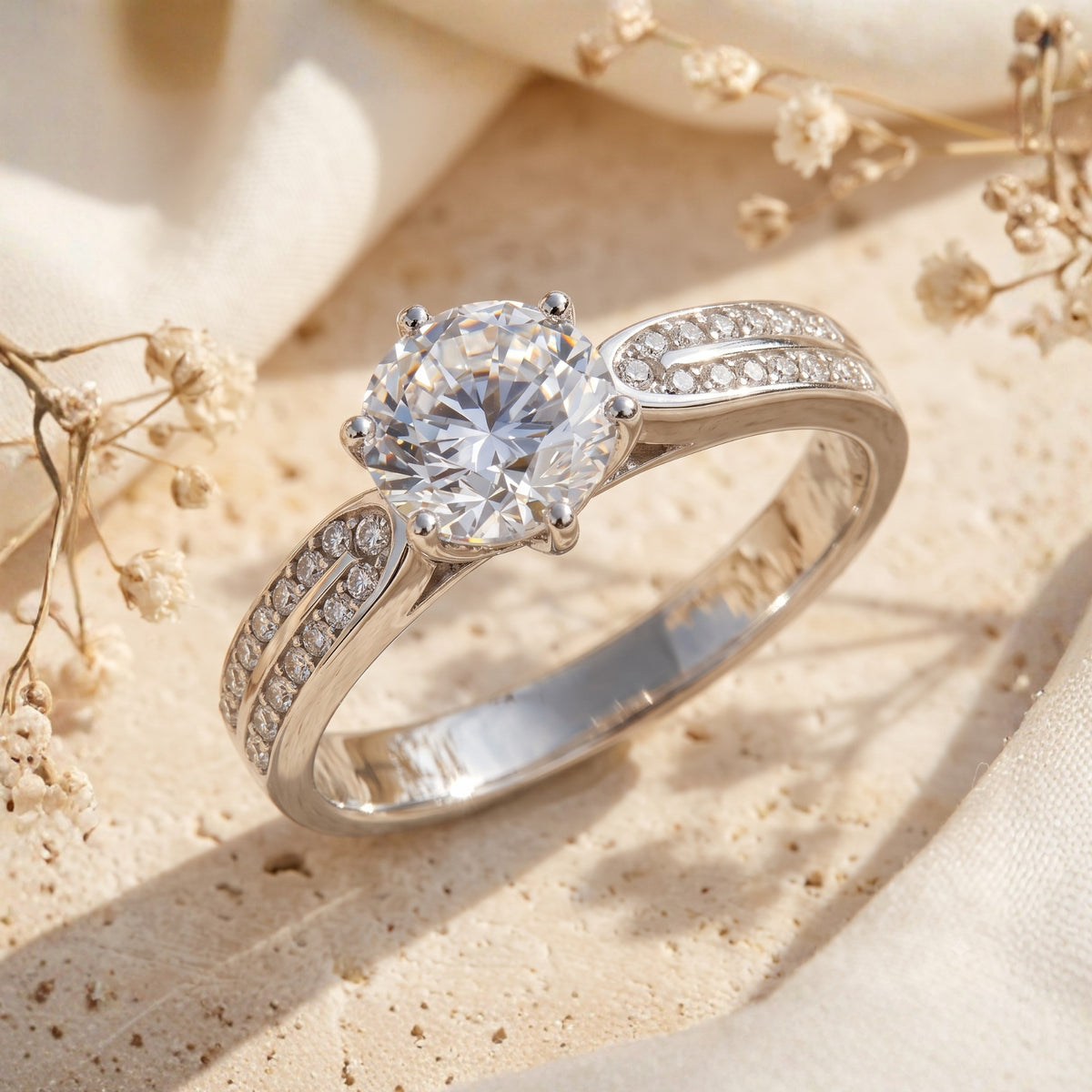 Angled close-up of a silver split-shank ring with a six-prong round center stone and double rows of pave accents.