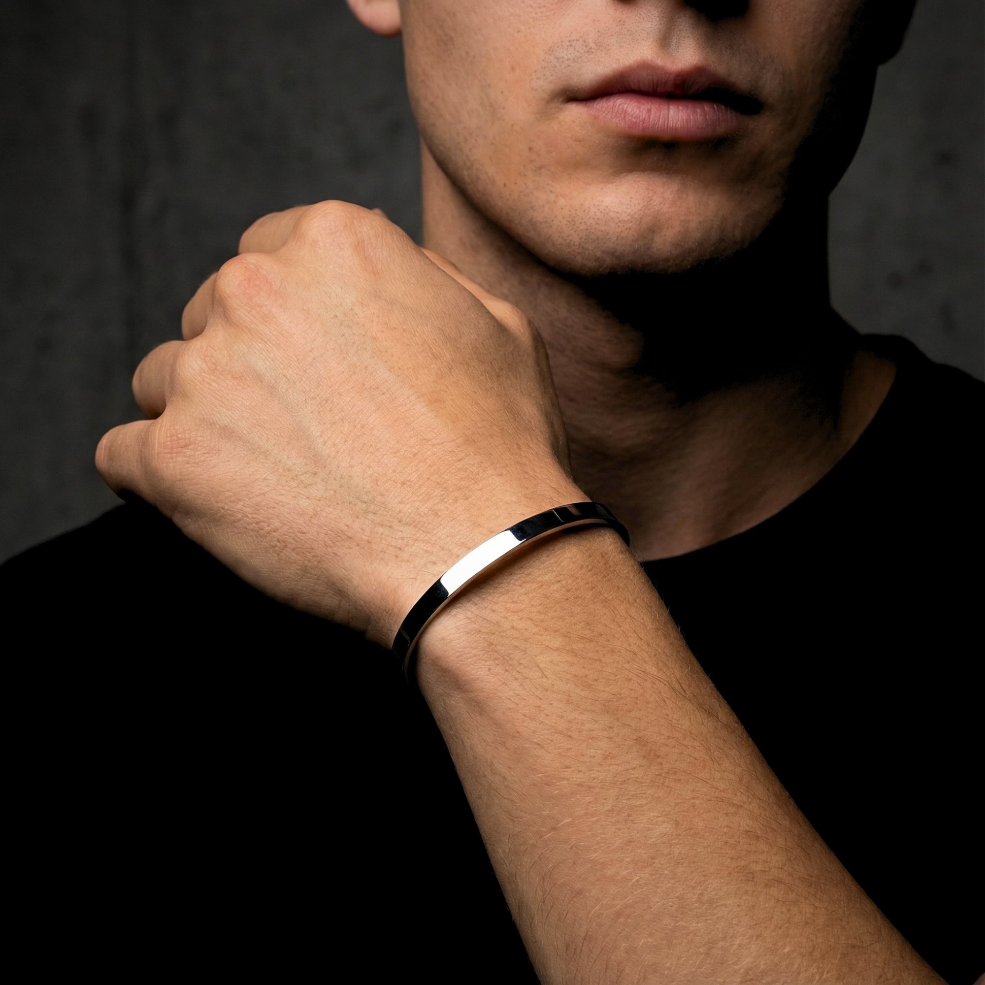 Men's silver stainless steel cuff bracelet worn on a wrist, paired with a black t-shirt.