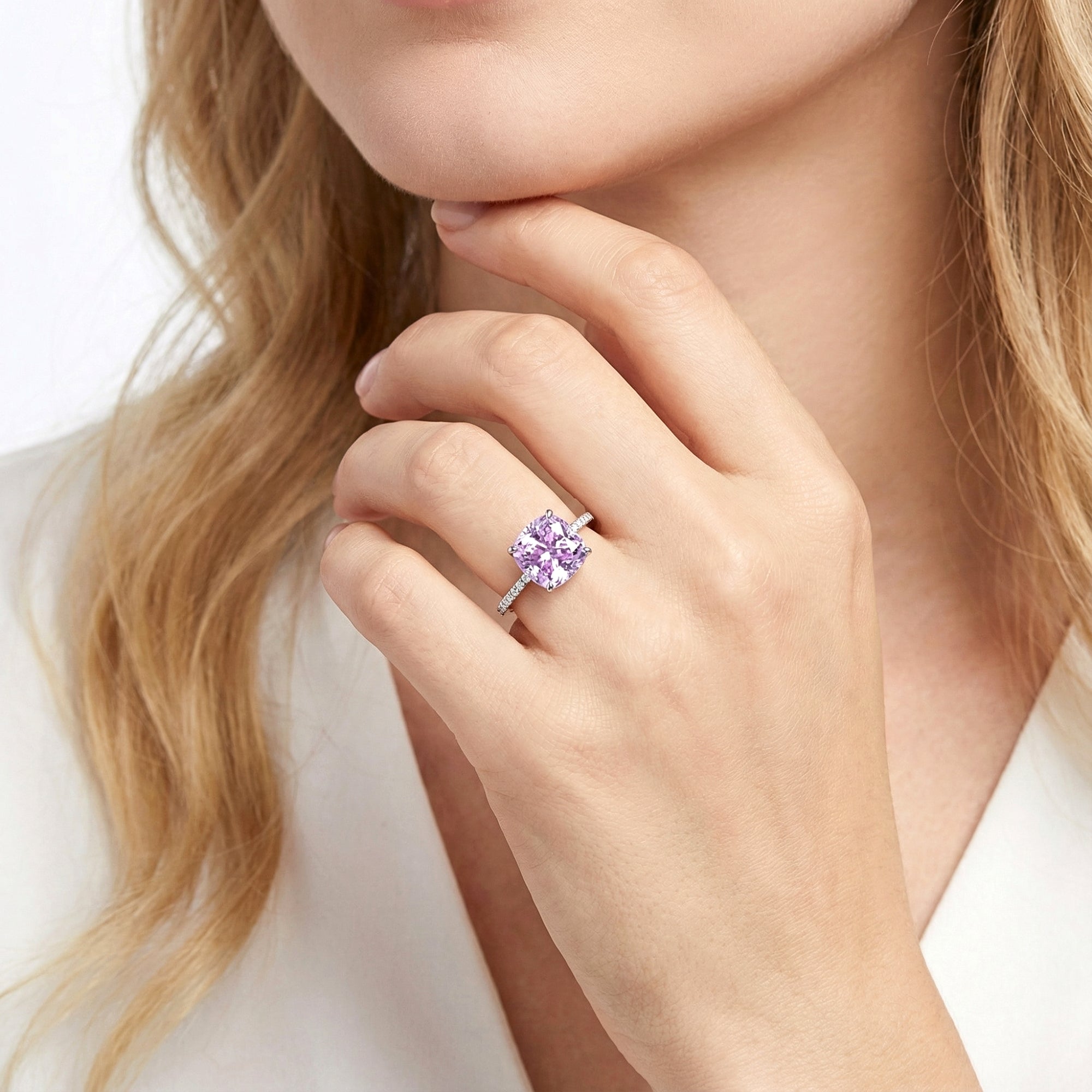 Model wearing the Ariadne cushion cut simulated amethyst halo ring in sterling silver on her ring finger.