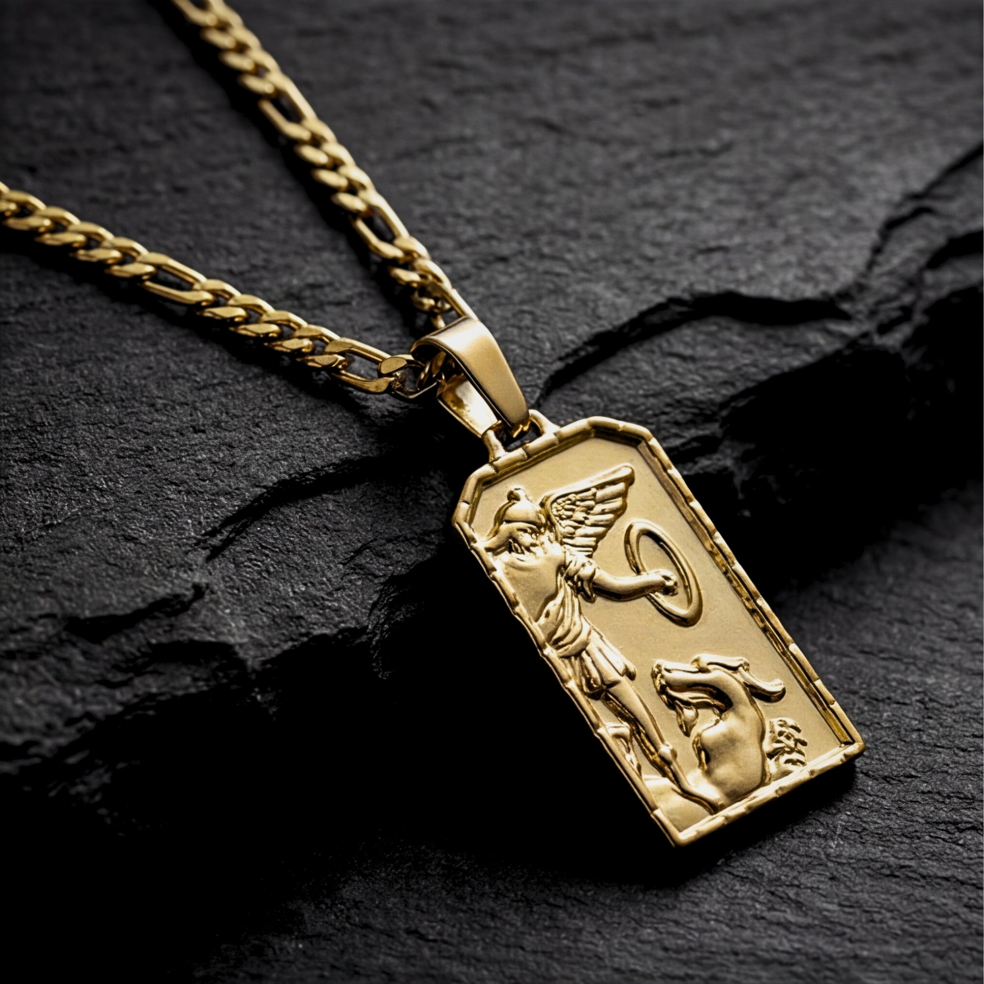 Angled close-up of the gold St. Michael Archangel pendant showing the detailed embossed religious figure and border.